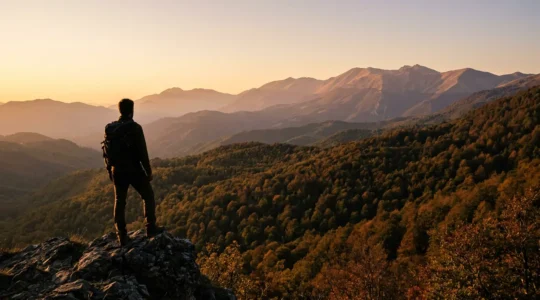 Escursionista che osserva il panorama montano di un parco nazionale italiano al tramonto, con vallate boscose e vette appenniniche sullo sfondo